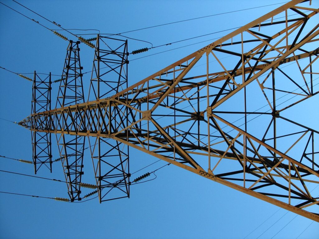 Electric transmission tower and power lines against blue sky